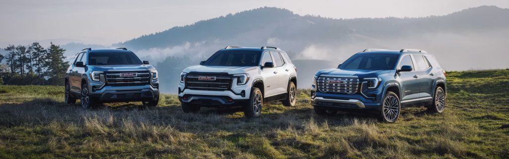 Three GMC Terrain SUVs on a scenic hillside.
