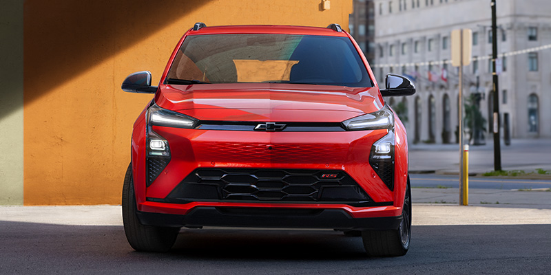 Front view of a red Chevrolet SUV parked on a city street beside a building.