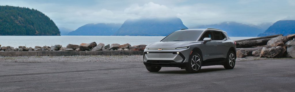 Gray Chevrolet electric SUV parked near a scenic waterfront landscape.