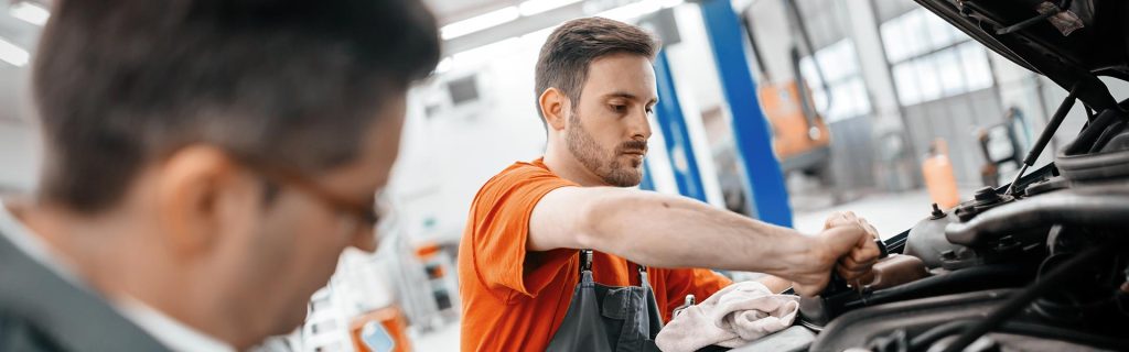 Mechanic performing vehicle service and maintenance in an auto repair shop.