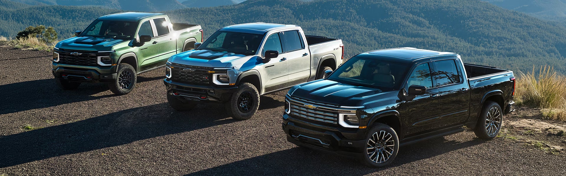 Chevrolet Silverado pickup trucks in a mountain setting.