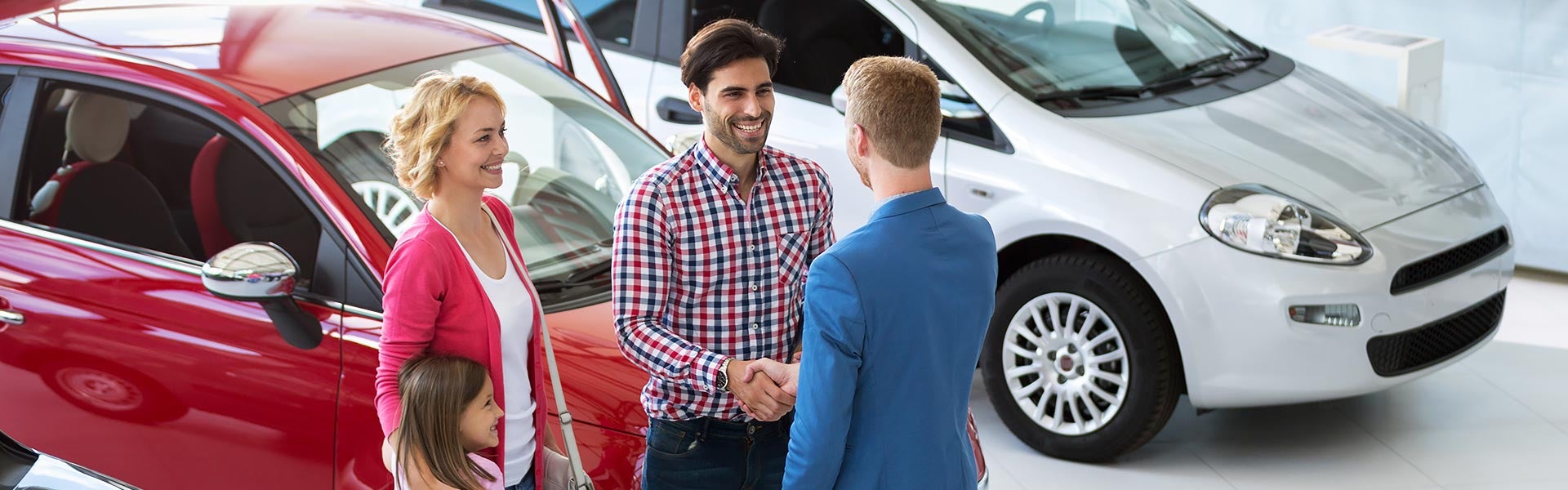 Car dealership salesperson discussing a vehicle with customers.