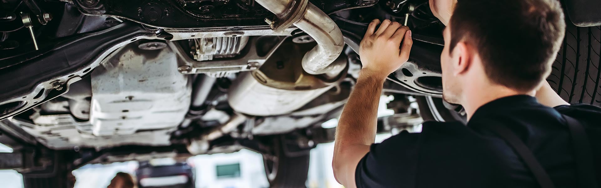 Mechanic inspecting a vehicle undercarriage.